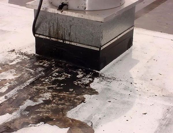 Grease buildup pooled on a restaurant roof around a rooftop exhaust fan